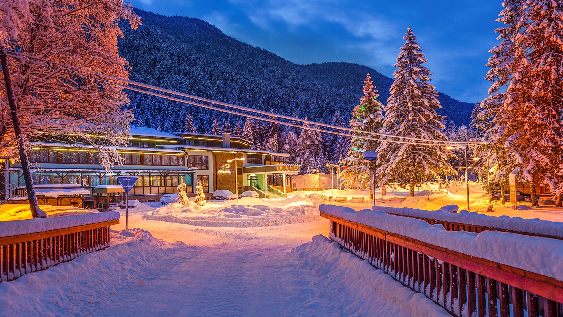 Zasnežená cesta k rozsvietenému hotelu za súmraku